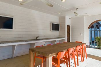 A dining area with a long table and orange chairs.